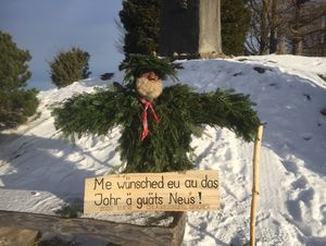 Puppe Silvesterchlaus mit Schild in Schneefeld